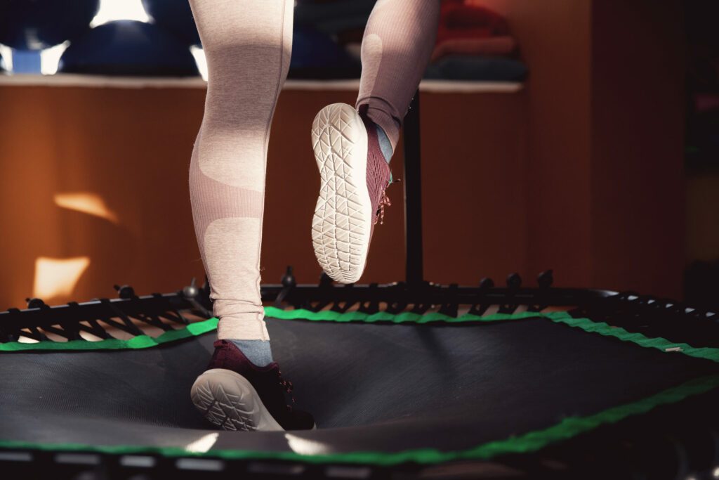 Closeup step fitness woman jumping on mobile mini trampoline